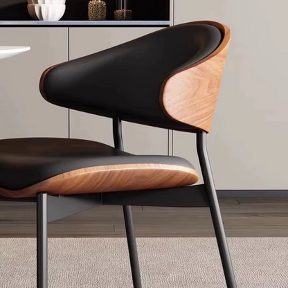 Close up of the rich walnut wood frame and smooth leather upholstery on a dining table chair